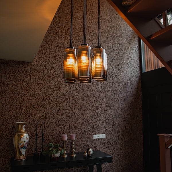 Drei Pendelleuchten aus Glas über einem Tisch mit Dekorationsgegenständen in einem eleganten Raum.