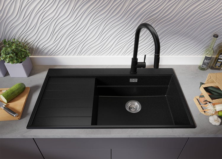 Schwarze Küchenspüle mit Abtropffläche und schwarzer Armatur auf einer Küchentheke.