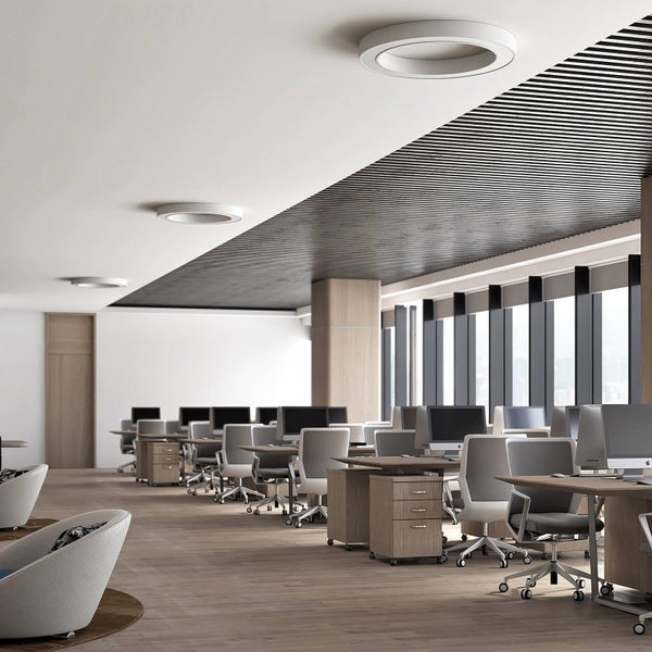 Hell, großräumig organisiertes Großraumbüro mit Holzschreibtischen, ergonomischen Bürostühlen, großen Fenstern und runden Deckenleuchten.