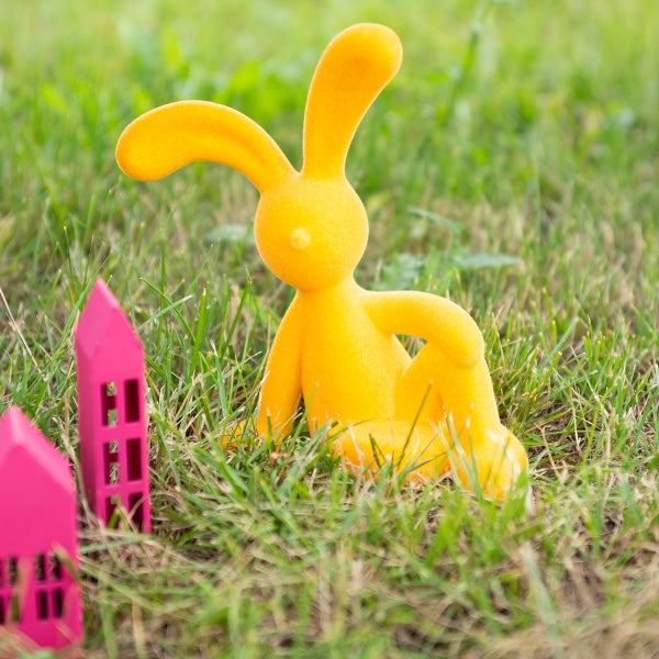 Gelber Osterhase und rosa Häuser im Gras