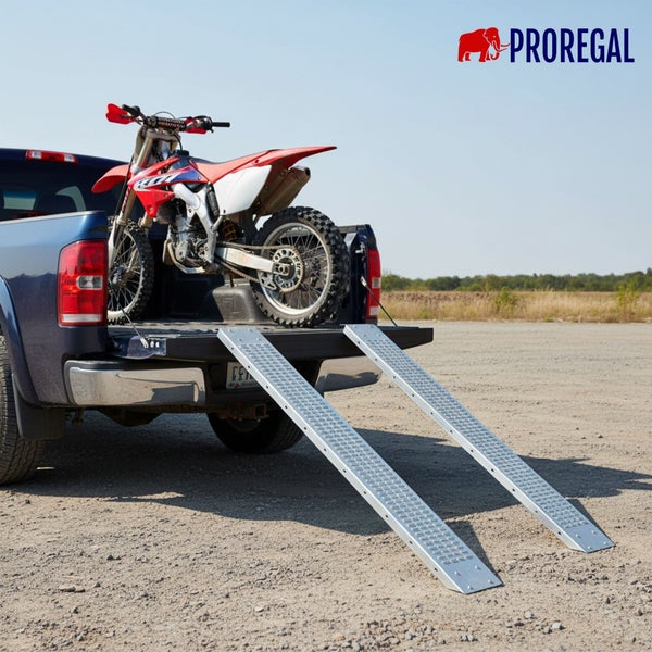 Zwei Auffahrrampen aus Metall an der Ladefläche eines Pickups mit einem geladenen Motocross Motorrad. Proregal Logo.