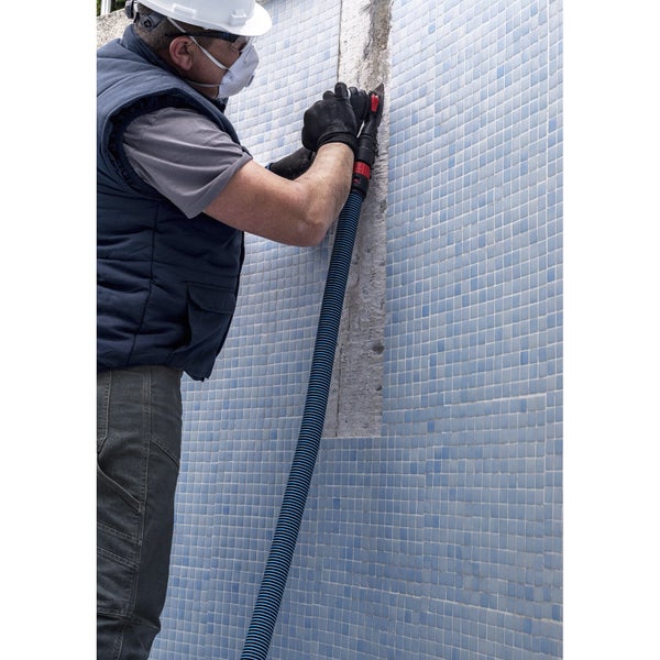 Handwerker bei der Fugensanierung an einer Wand mit blauem Mosaik