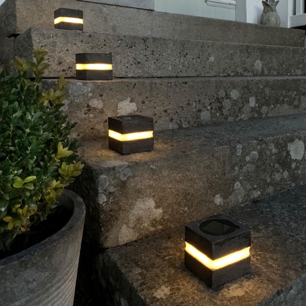 Mehrere quadratische Außenleuchten auf einer Treppe mit Bepflanzung