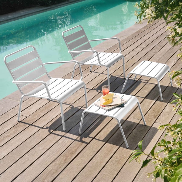 Heller, moderner Gartenbereich am Pool mit zwei Loungesesseln und zwei Beistelltischen aus Metall auf einer Holzterrasse.