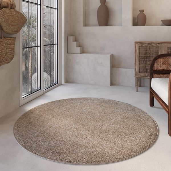 Runder, strukturierter Teppich in einem hellen, minimalistischen Wohnraum mit Holzmöbeln und natürlichen Dekorationselementen.