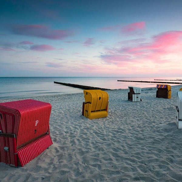 Strandszene mit mehreren Strandkörben am Meer bei Sonnenaufgang
