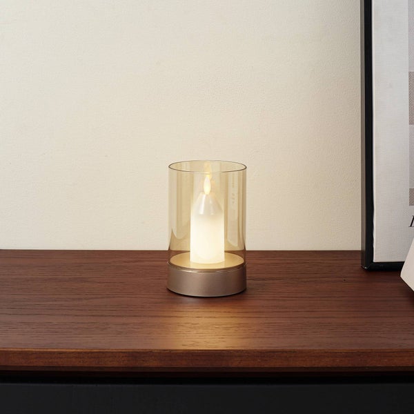 Dekorative LED-Kerze in einem Glaswindlicht mit rundem Sockel auf einer Holzoberfläche.