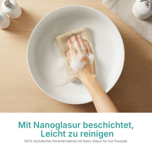 Hand, die ein weißes Keramik-Waschbecken mit Nanoglasur und Seifenschaum auf einer Holzoberfläche reinigt.
