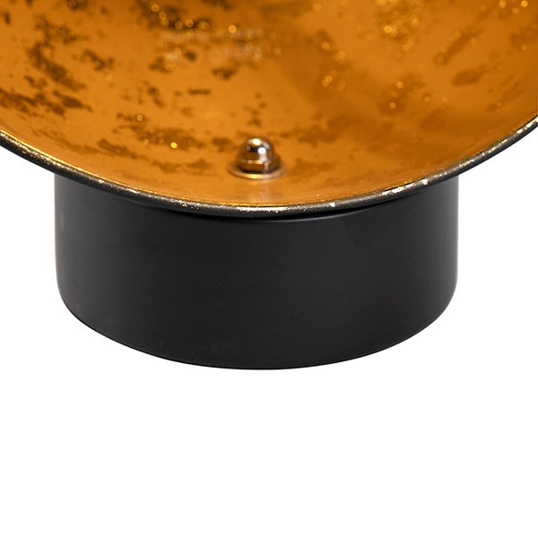 Detailaufnahme eines goldenen Lampenschirms mit schwarzem Lampenfuß