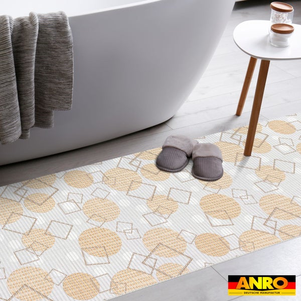 Badläufer mit geometrischem Muster aus Kreisen und Quadraten im hellen Badezimmer neben freistehender Badewanne und Beistelltisch. ANRO Logo.