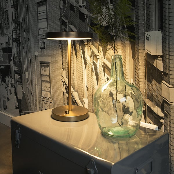 Tischleuchte neben einer Glasvase auf einem Schrank