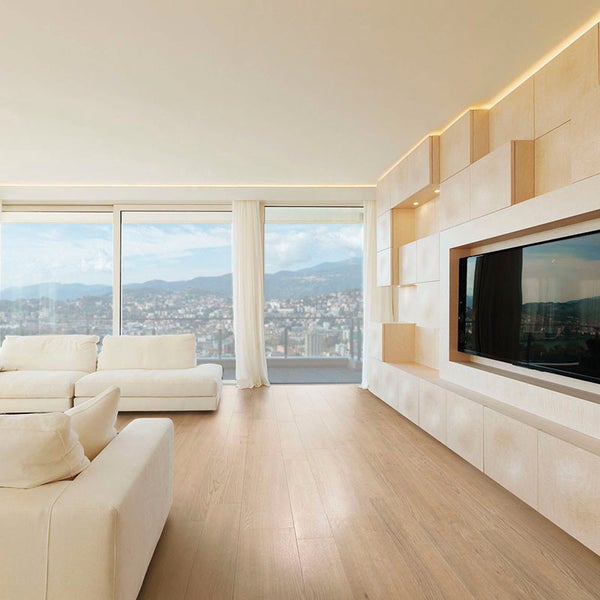 Modernes Wohnzimmer mit hellem Parkettboden, weißem Sofa und maßgefertigter Wandverkleidung aus Holz mit integriertem Fernseher und Beleuchtung.