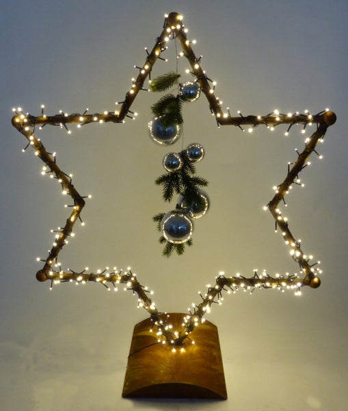 Weihnachtsstern aus Zweigen mit LED Lichterkette und Dekokugeln auf Holzsockel als Tischdekoration