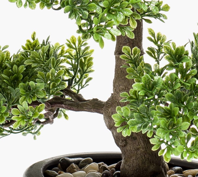 Künstlicher Bonsai mit braunem Stamm, grünen Blättern und Zierkies im Topf.