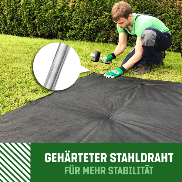 Ein Mann befestigt ein Unkrautvlies mit einem Hammer und Erdnägeln im Garten, Nahaufnahme eines Erdnagels aus gehärtetem Stahldraht