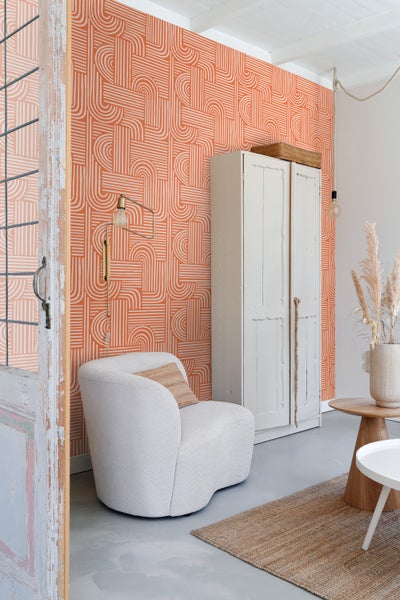 Wohnraum mit orangefarbener Tapete, Sessel und Schrank