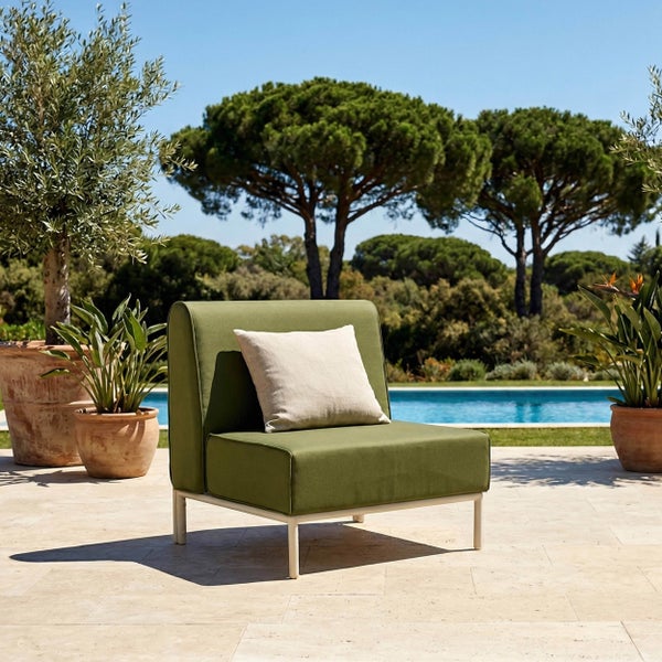 Moderner Outdoor-Loungesessel mit grünen Polstern und weißem Gestell auf einer hellen Terrasse am Pool, umgeben von Pflanzen und Bäumen.