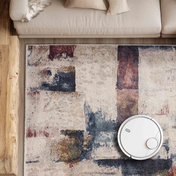 Saugroboter auf einem gemusterten Teppich in einem Wohnzimmer