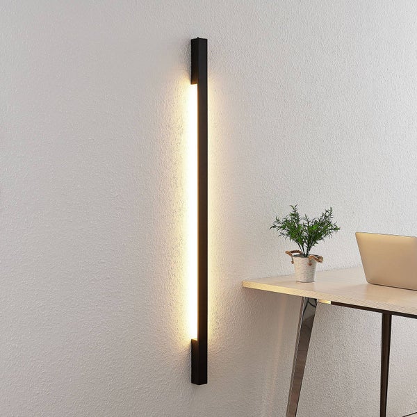 Schwarze vertikale LED-Wandleuchte mit warmem indirektem Licht in einer modernen Büroumgebung.