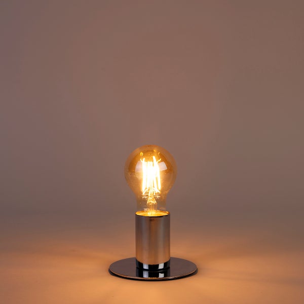 Minimalistische Tischleuchte mit silberfarbenem Metallsockel und leuchtender Filament-Glühbirne.