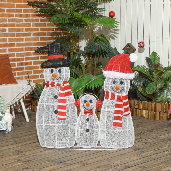 Drei dekorative LED-Schneemänner aus weißem Drahtgeflecht mit Hüten und Schals auf einer Holzterrasse vor einer Ziegelwand.
