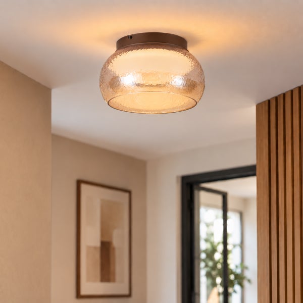 Moderne Deckenleuchte mit kuppelförmigem, strukturiertem Glasschirm und runder Deckenhalterung in einem Wohnraum mit Holzlamellen.