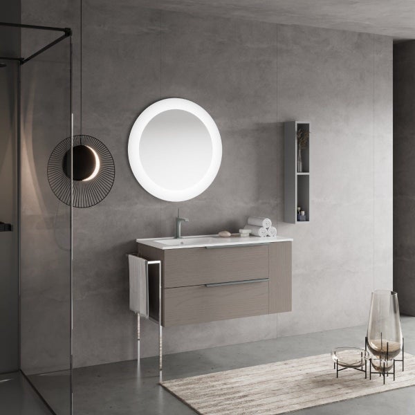 Modernes Badezimmer mit Waschtisch, zwei Schubladen, rundem beleuchtetem Spiegel, Handtuchhalter und Wandregal vor einer grauen Betonwand.