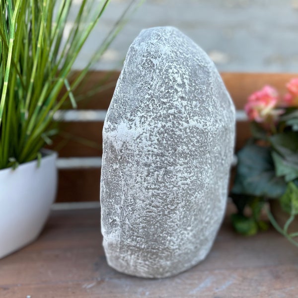 Dekorativer künstlicher Stein mit strukturierter Oberfläche für den Garten, auf einer Holzoberfläche.