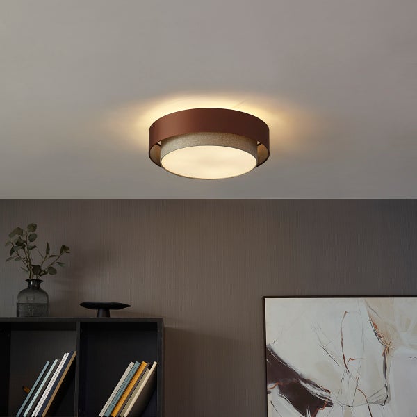 Moderne, runde Deckenleuchte mit zweistufigem Schirm aus braunem Metall und strukturiertem Stoff in wohnlichem Ambiente.