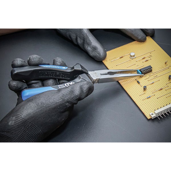 Hand mit Elektronikzange bearbeitet eine Platine mit elektronischen Bauteilen.