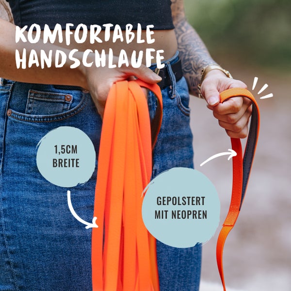 Frau hält eine orangefarbene Hundeleine mit einer Breite von 1,5 cm und einer gepolsterten Handschlaufe aus Neopren.
