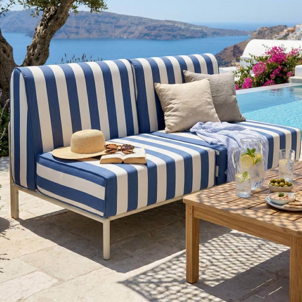 Garten-Lounge-Sofa mit blau-weiß gestreiften Polstern auf einer Terrasse am Pool mit Meerblick.