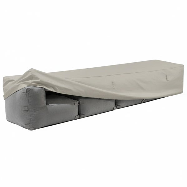 Beigefarbene Schutzhülle für Gartenmöbel, teilweise über ein graues Lounge-Sofa gezogen.