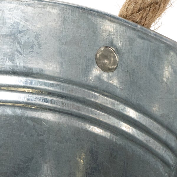 Detailansicht eines verzinkten Metalleimers mit einem Niet und einem Griff aus Seil.