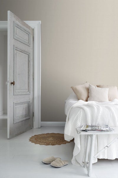 Schlafzimmer mit Bett, Beistelltisch und offenstehender Tür