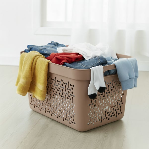 Wäschekorb gefüllt mit Kleidung und einem gelben Handtuch