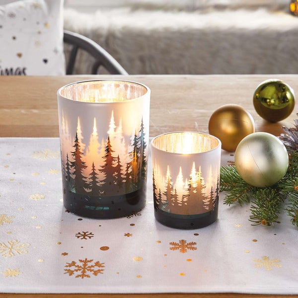 Zwei Windlichter mit Waldmotiv auf einem Tisch mit Weihnachtsdekoration