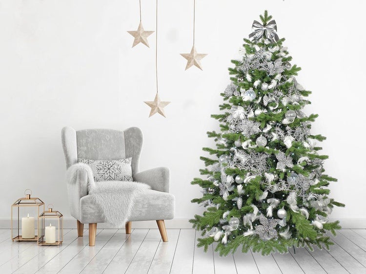 Geschmückter künstlicher Weihnachtsbaum in einem Wohnzimmer mit Sessel und hängenden Sternen.