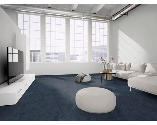 Moderner Wohnraum im Loft-Stil mit dunkelblauem Teppichboden, weißem Sofa, großen Fenstern und freiliegenden Deckenrohren.