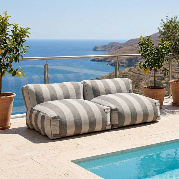 Gestreiftes Outdoor-Sitzsack-Sofa auf einer hellen Terrasse am Pool mit Meerblick und Zitronenbäumen.