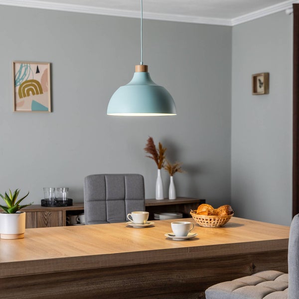 Moderne Pendelleuchte mit hellblauem Metallschirm und Holzdetail über einem Holzesstisch in einem hellen, modern eingerichteten Esszimmer.