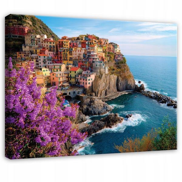 Leinwandbild mit buntem Küstendorf an Klippen am Meer und violetten Blumen im Vordergrund.
