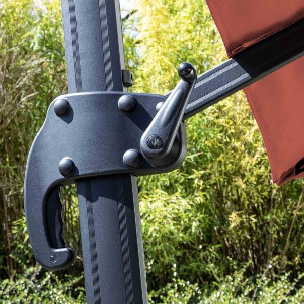 Moderner Garten-Loungebereich auf einer Holzterrasse mit einem großen roten Ampelschirm, einer Eckcouch mit grauen Polstern und integrierten Tischen.