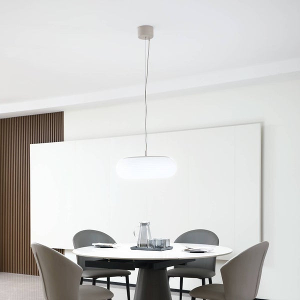 Moderne ovale Pendelleuchte in Weiß über einem runden Esstisch mit grauen Stühlen in einem hellen, minimalistischen Raum.