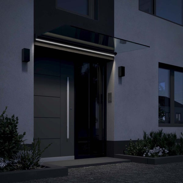 Modernes Vordach aus Glas mit integrierter LED-Beleuchtung über einem Hauseingang bei Nacht.