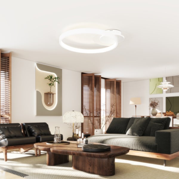 Wohnzimmer mit Sofa, Sesseln, Holztisch und ringförmiger Deckenleuchte