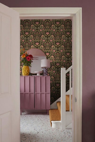 Fluransicht mit floraler Tapete, Kommode, Spiegel und Treppe