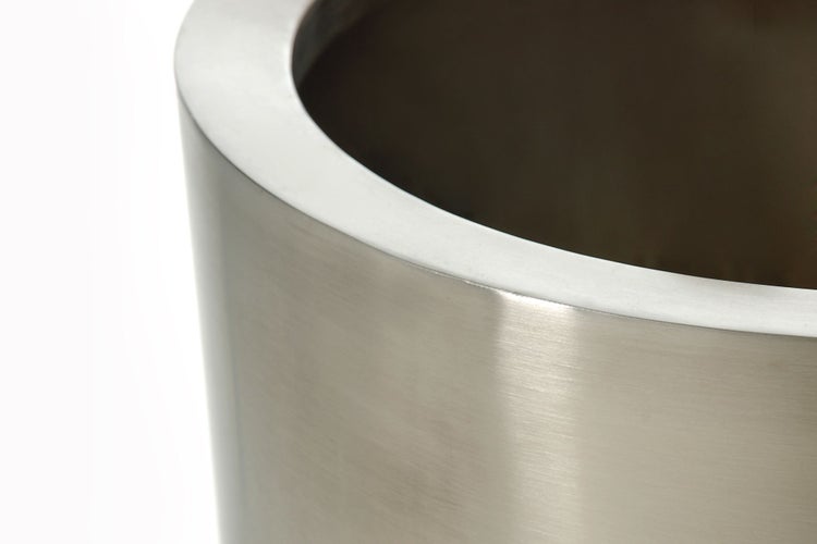 Nahaufnahme eines runden Pflanzgefäßes aus gebürstetem Metall mit breitem Rand.