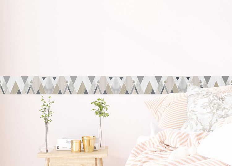 Tapetenbordüre mit geometrischem Dreiecksmuster in Grau und Beige an einer hellen Wand im Schlafzimmer mit Nachttisch aus Holz und hellem Bett.