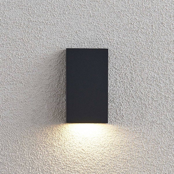 Schwarze rechteckige Außenwandleuchte mit nach unten gerichtetem Lichtstrahl an einer Fassade.
